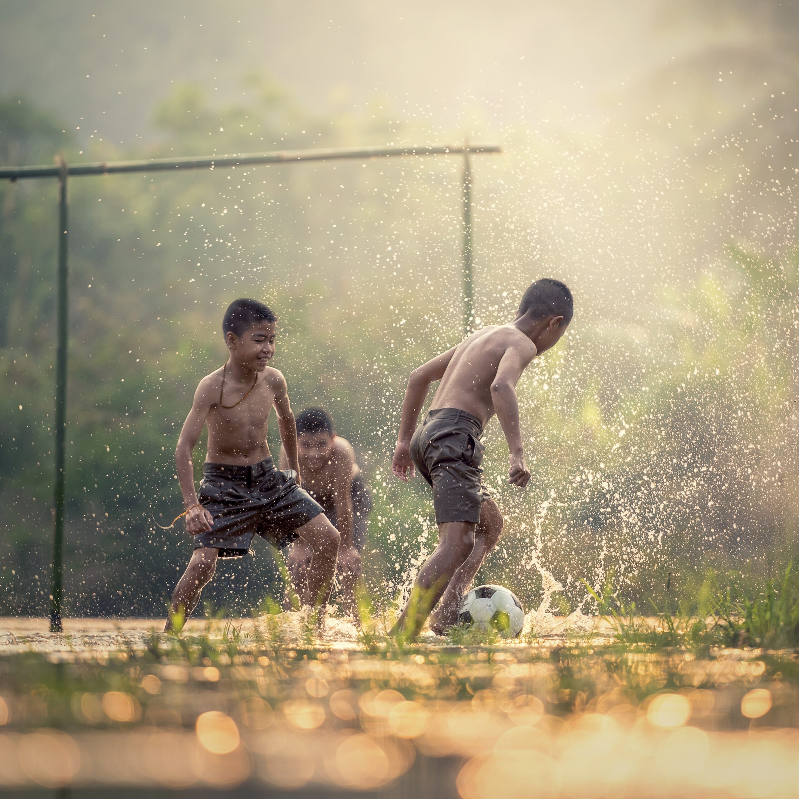 Young Filipino children playing football on a village pitch, highlighting community-based sports.