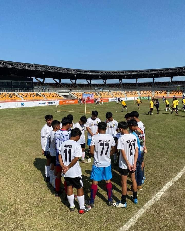 WLAC Football Club players huddle in prayer before their match at a football stadium.