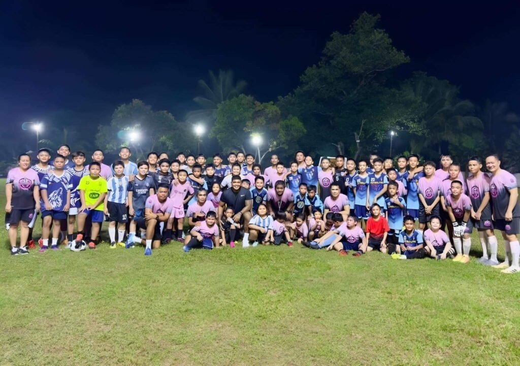 Dumaguete Elite Football Academy players and coaches united on the training field during a night session, promoting teamwork and youth football development in Dumaguete City.