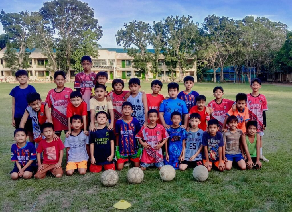 Young football players of Milagros United Football Club posing on the field in Masbate, showing the future of grassroots football in the Philippines.