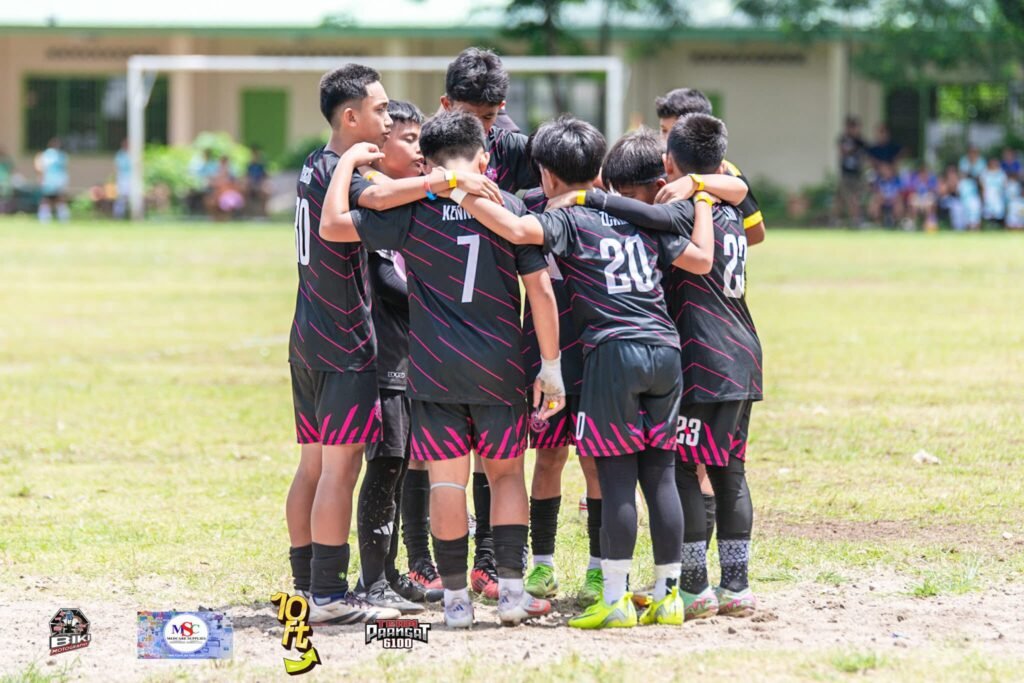 Youth football players from Dumaguete Elite Football Academy huddle together before a match, showing teamwork, unity, and sportsmanship during a grassroots tournament in the Philippines.