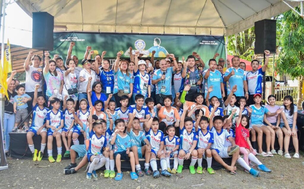 Members of Isabel Football Club celebrating with young players and parents during a football event in Iligan City.