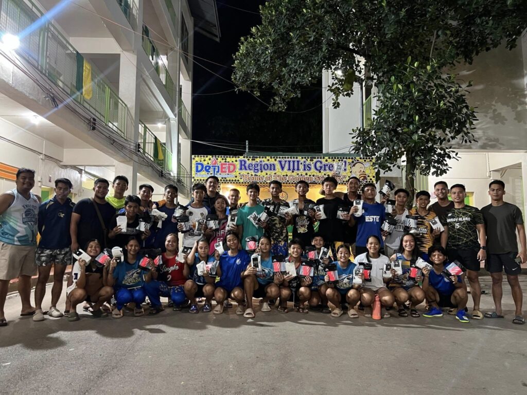 Group photo of Taft/Tubignon FC players and coaches holding gear, standing together outdoors at night during a team gathering in Eastern Samar.