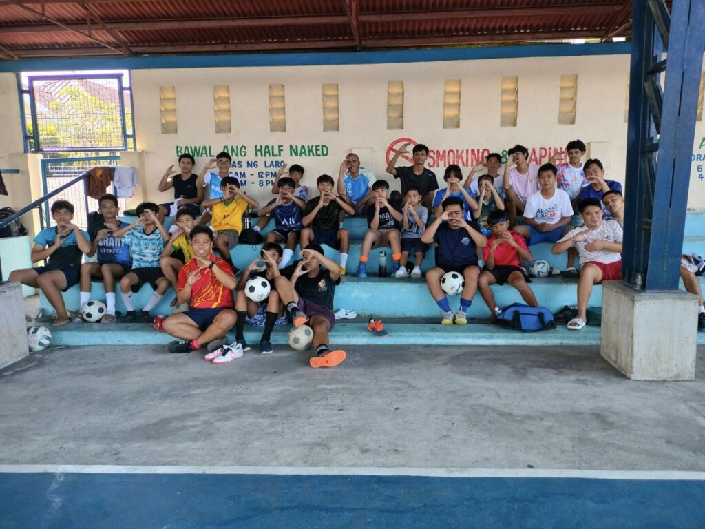 Youth players of Orani Strikers Football Club sitting together after training in Orani, Bataan