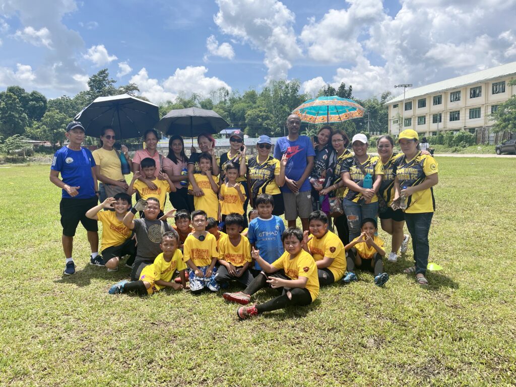 Youth players of Juventud Pototan Football Club, a Philippine football posing with parents, coaches, and supporters on the field during a community football event in Pototan, Iloilo.