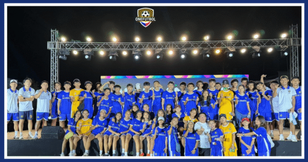 Youth players and coaches gathered on stage during a Philippine football community celebration event hosted by One Futbol.