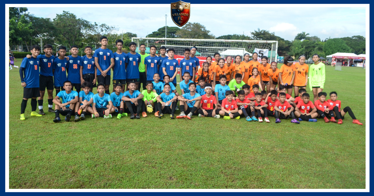 Villamor Football Club players and coaches posing together on a football field during a team gathering.