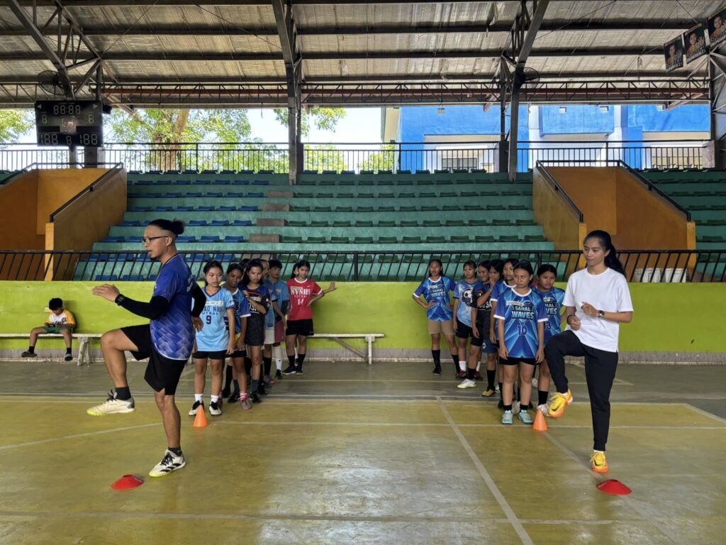 Coaches demonstrate warm-up drills for young football players during an Island Grafika Football Academy training session in Samal.